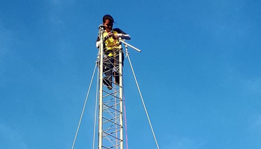 Image description: A person high up on a communications tower. Image source: Village Base Station Project, University of the Philippines